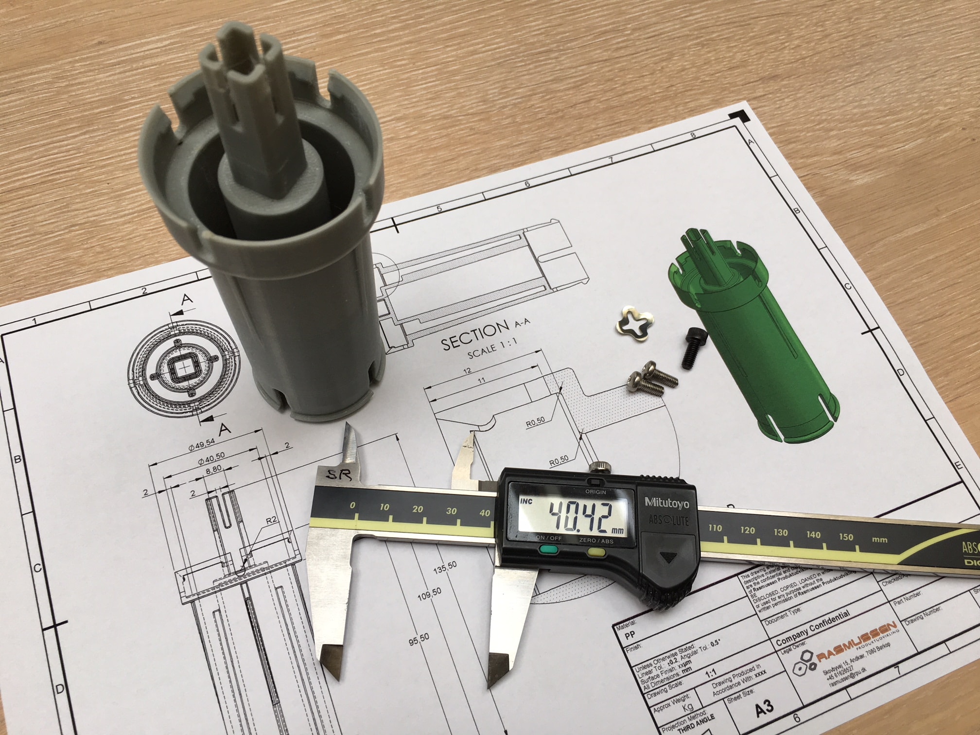 3D printet prototype vist fysisk sammen med 2D tegningen under